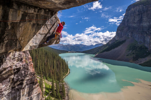 Person rock climbing with Fairmont Lake Louise in the background