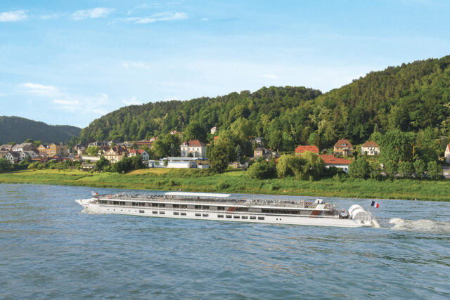 Boat cruising on a river passing houses and trees