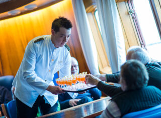 Waiter serving welcome drinks on MS Lofoten