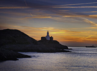 Mumbles Head lighthouse at sunrise from Bracelet Bay