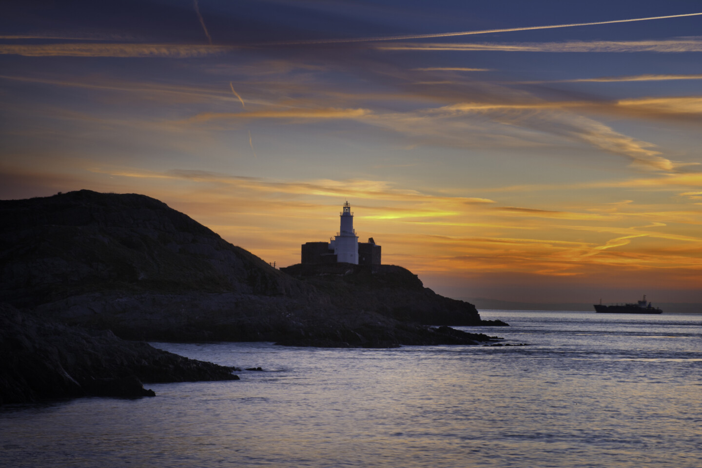 Mumbles Head lighthouse at sunrise from Bracelet Bay