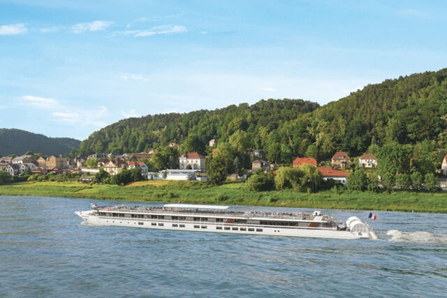 Boat cruising on a river passing houses and trees