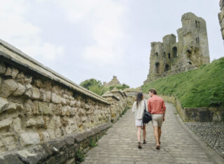 Couple walking up a sloped path, ruins
